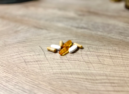 A close-up view of various vitamin pills arranged neatly on a wooden table surface.