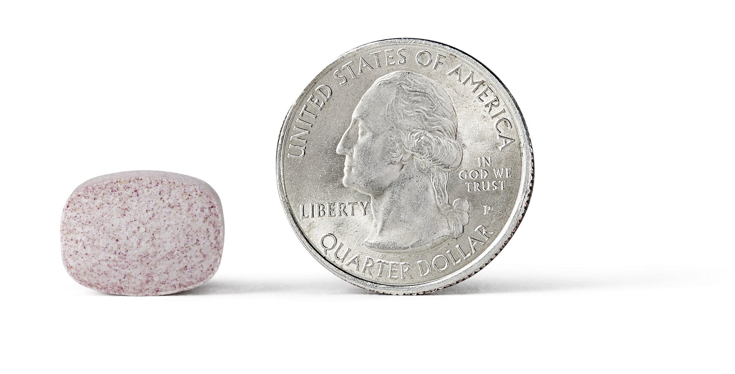 An Airborne Berry Chewable Tablet placed next to a quarter for size comparison.