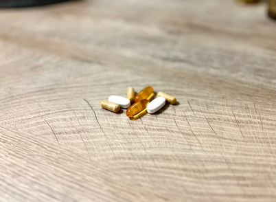 A close-up view of various vitamin pills arranged neatly on a wooden table surface. 